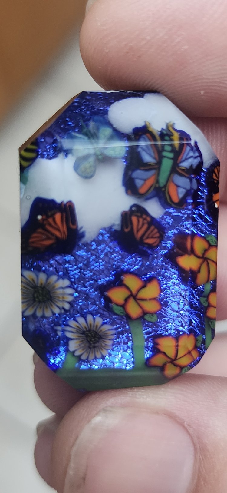 Decorative millie glass showing butterflies and flowers against sparkling blue